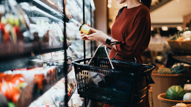 Woman carrying a shopping basket in grocery store 