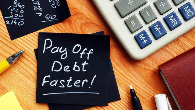 Pay off debt faster handwritten memo and calculator. 