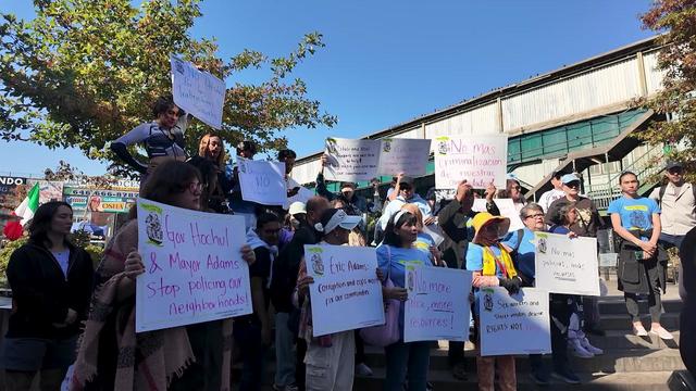 Dozens rally with signs to oppose a crackdown on illegal brothels, sex trafficking and unlicensed vendors. 