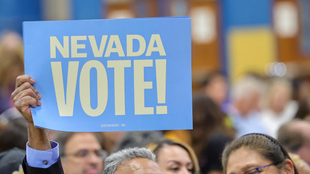 Man holds "Nevada Vote!" sign at a campaign rally 