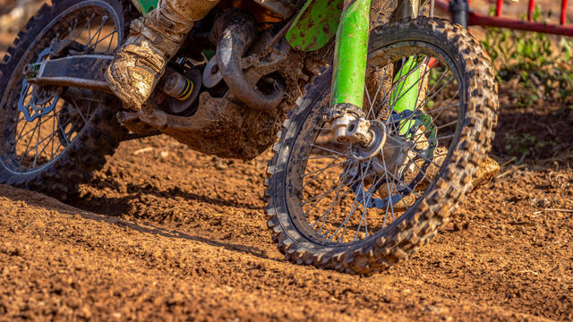 Dirty wheels, engine and boots on a muddy off-road motorcycle on a muddy off-road motorcycle on a wet dirt track in the mountains 