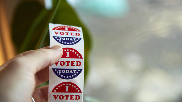 A person taking an "I Voted Today" sticker after casting their ballot. 