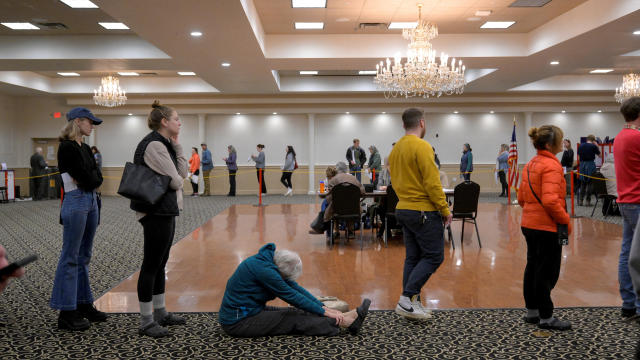 A woman sits and stretches as she waits to vote because the Italian Heritage Center has had a line over an hour long since 7 a.m. in Maine's 2nd Congressional District during the 2024 U.S. presidential election on Election Day in Portland, Maine, Nov. 5,  