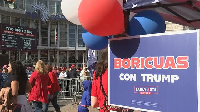 A sign outside a Trump rally says Boricuas con Trump, people are walking around near the PPL Center 