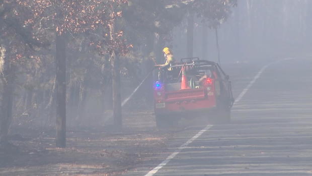 A person is spraying water from a truck, conditions are smoky and hazy 