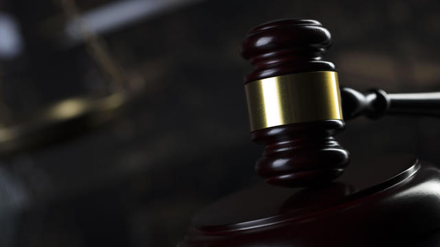 Close-up of gavel on books against black background 