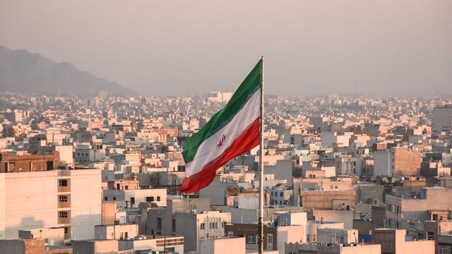 Iranian flag waving with city skyline on background in Tehran, Iran 