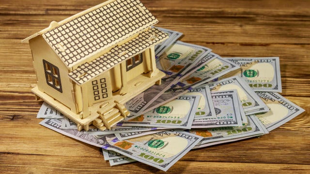 House model and U.S. one hundred dollar bills on wooden background. Property investment, home loan, house mortgage, real estate concept 