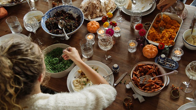 Teenage girl having food while sitting at dining table during Thanksgiving