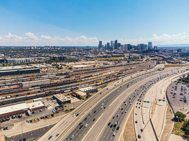 A High Angle View of Interstate 25 Traffic Passing a Large Railyard with Trains and Freght Cars North of Denver, Colorado near "The Mousetrap" Highway Interchange 