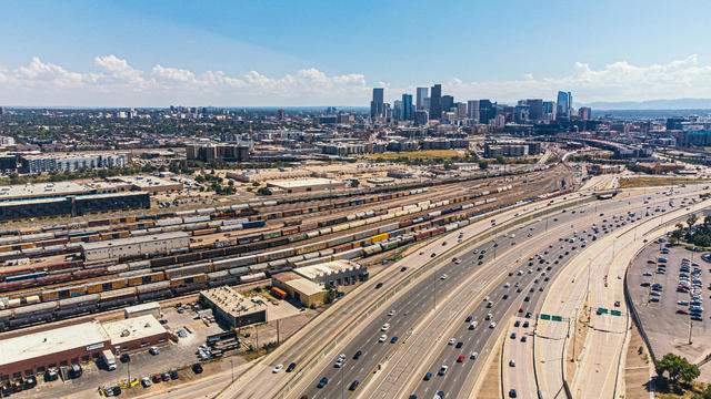 A High Angle View of Interstate 25 Traffic Passing a Large Railyard with Trains and Freght Cars North of Denver, Colorado near "The Mousetrap" Highway Interchange 