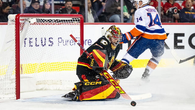 Calgary Flames Goaltender Dustin Wolf (32) stops New York Islanders Center Bo Horvat (14) during the first period of an NHL game on November 19, 2024, at the Scotiabank Saddledome in Calgary, AB. 