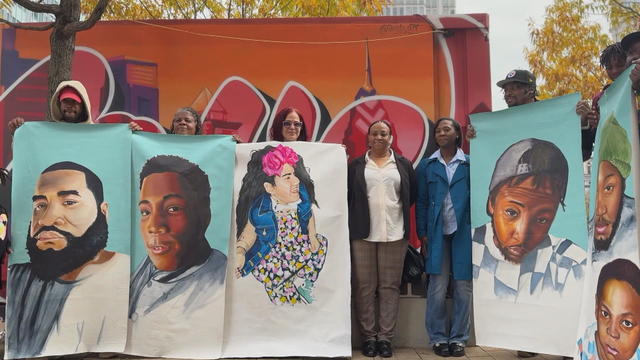 Family members hold the large portraits of their loved ones lost to violence 