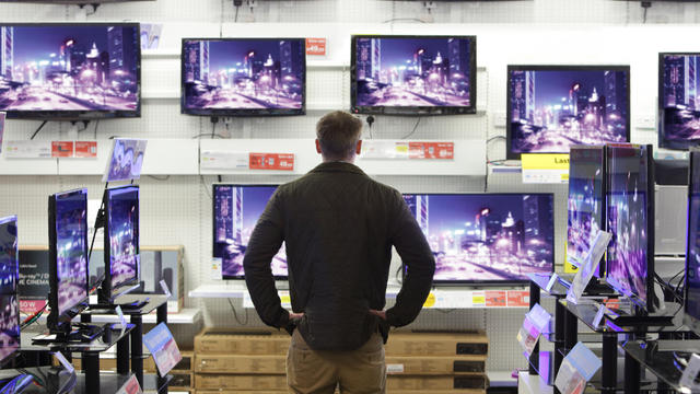 Man stood in shop surrounded by televisions 