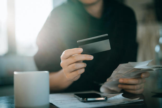 Cropped shot of young Asian woman holding credit card and expense receipts, handing personal banking and finance at home. Planning budget, calculating expenses and managing financial bills. Home budgeting. Home finances. Digital banking habits 