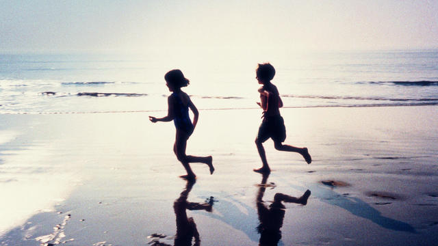 BOY AND GIRL IN SILHOUETTE, RUNNING ALONG THE BEACH 