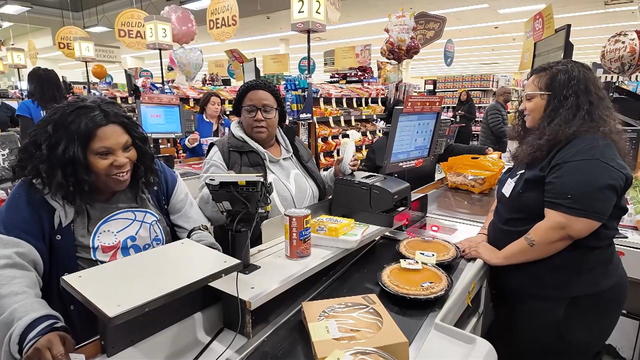 Shoppers wait for their pies and other food to move down the belt at an Acme store 