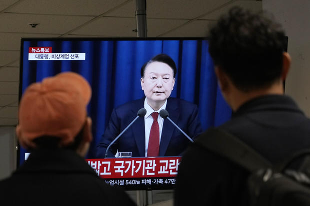 People watch a TV screen showing South Korean President Yoon Suk Yeol's televised briefing at a bus terminal in Seoul, South Korea, Dec. 3, 2024. 