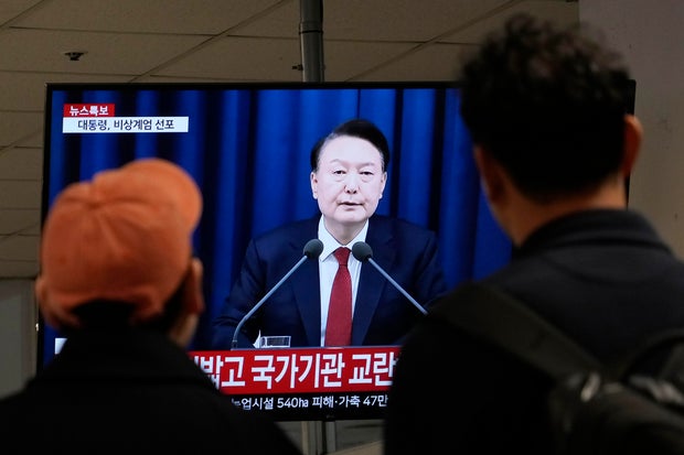 People watch a TV screen showing South Korean President Yoon Suk Yeol's televised briefing at a bus terminal in Seoul, South Korea, Dec. 3, 2024.