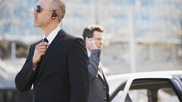 Bodyguard protecting politician in backseat of car 