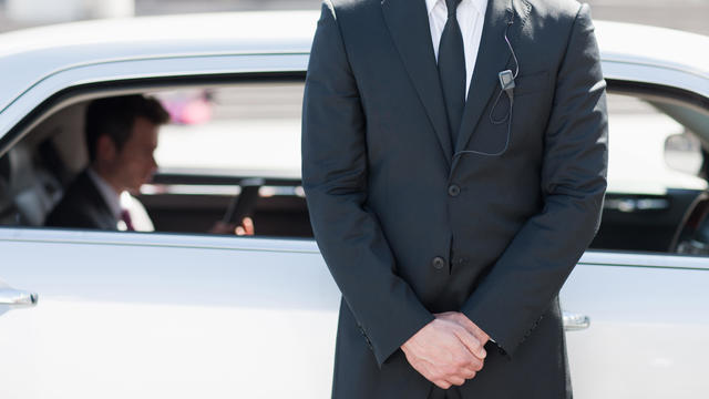 Bodyguard protecting politician in backseat of car 