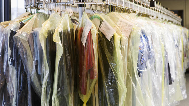 Dry cleaning wrapped in plastic on rack 