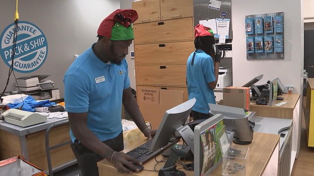 Workers at a UPS store wearing elf hats 