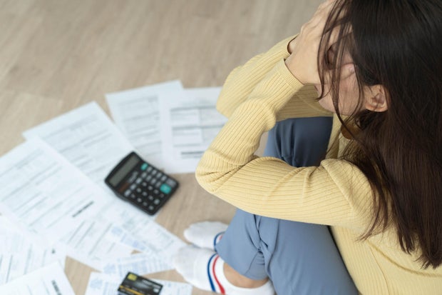 Women stress about a lot of credit card debt and bills on the floor. The housewife has trouble calculating monthly expenses and the budget is not enough to pay off the debt