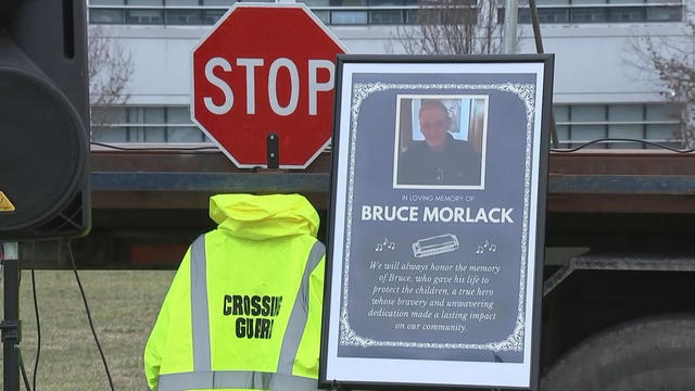 A stop sign, crossing guard jacket and poster are seen at a memorial for Bruce Morlack 