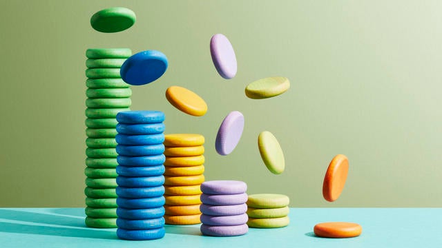 Six stacks of coloured coins with more coins falling onto them 