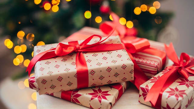 Group of Christmas gifts in front of tree. 