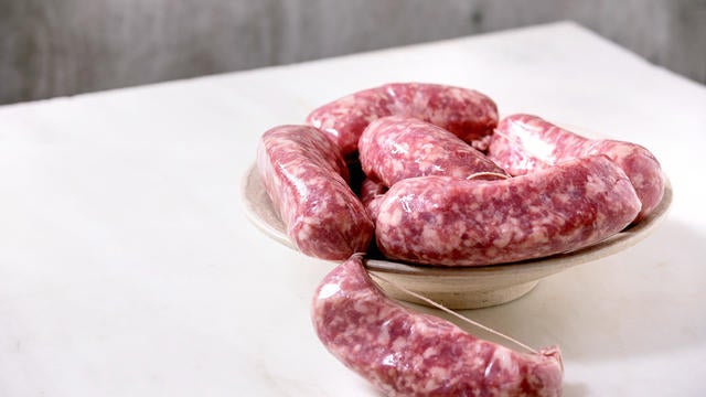 Raw uncooked italian sausages salsiccia in plate on white marble table. 