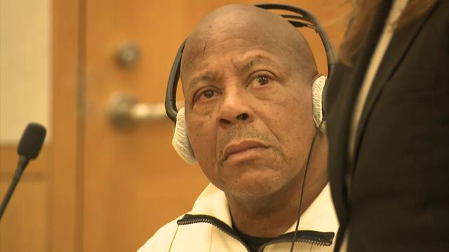 Jeffrey Koonce sits in court and wears headphones. 