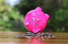 Piggy bank upside down on the pile of coins isolated on the table. 