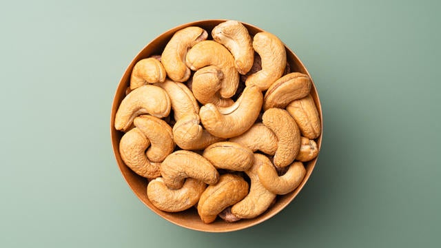 Cashew Nuts in Wooden Bowl on Green Background 