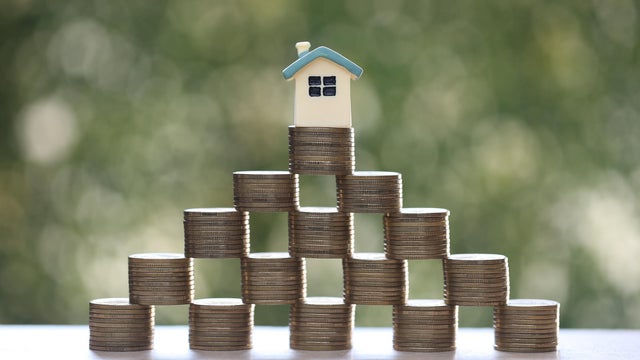 Mortgage,Model house and stack of coins money on natural green background,Business investment and real estate concept 