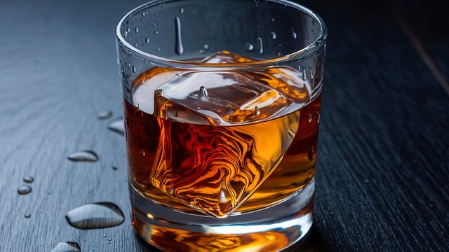 A glass of whiskey with an ice cube