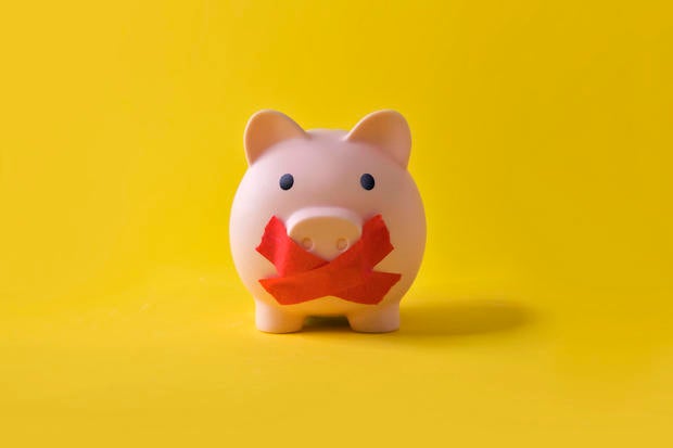 Piggy bank with a cross covering it's mouth. 