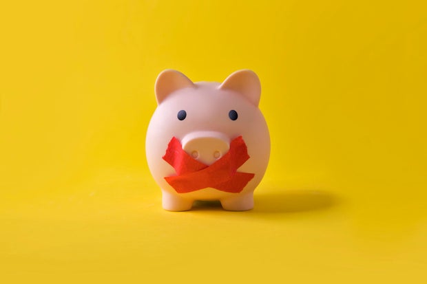 Piggy bank with a cross covering it's mouth.