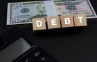 Debt Text On Wood Block With US Paper Currency and Calculator 