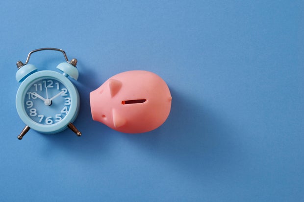 antique alarm clock and piggybank on blue background