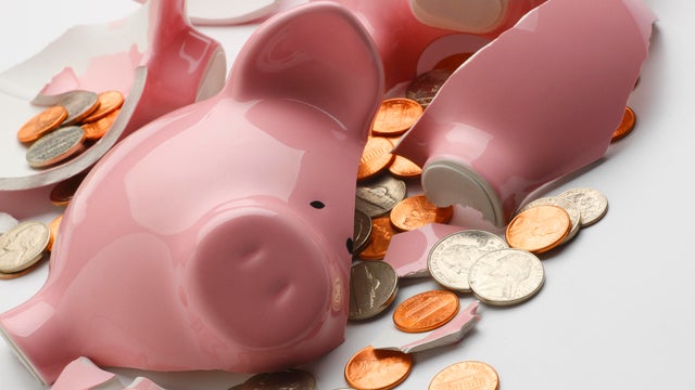 Coins strewn around broken pink piggy bank 