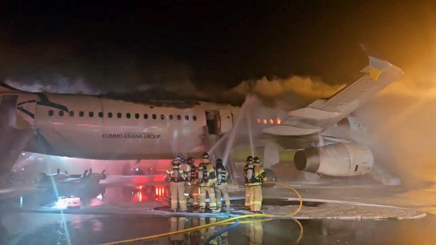 Os bombeiros tentam desligar o fogo de um avião de ônibus no Aeroporto Internacional Gimhae