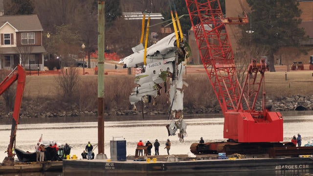 A crane retrieves part of the wreckage of American Eagle Flight 5342 from the Potomac River, in the aftermath of the deadly midair collision between the plane and an Army Black Hawk helicopter, by Ronald Reagan Washington National Airport, in Arlington, Virginia, Feb. 3, 2025. 