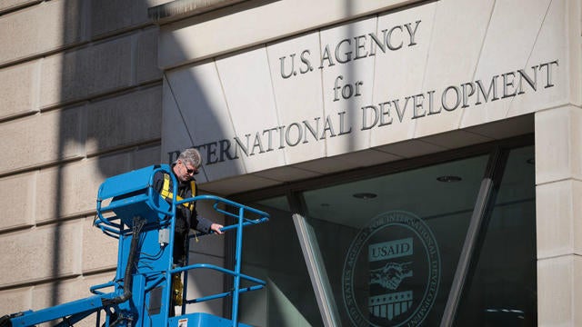 A worker removes the U.S. Agency for International Development sign from its headquarters in Washington, D.C., on Feb. 7, 2025 