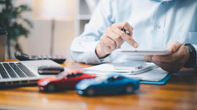 Toy Car In Front Of Businessman Calculating Loan. Saving money for car concept, trade car for cash concept, finance concept. 