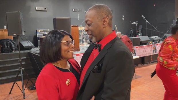 A couple wearing red and black dance on the dance floor 