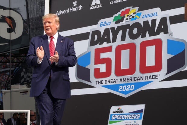 President Donald Trump speaks as first lady Melania Trump looks on from Victory Lane before Daytona 500 in Daytona Beach, Florida, on Feb. 16, 2020. 