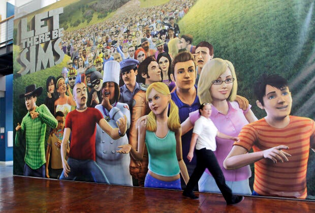 An employee passes a poster for The Sims 3 video game in the cafeteria of the Electronic Arts Inc. headquarters in Redwood City, California, July 20, 2010.