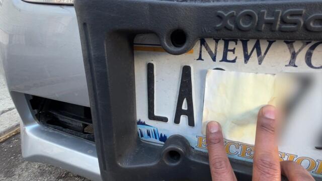 An individual stencils film onto his license plate. 